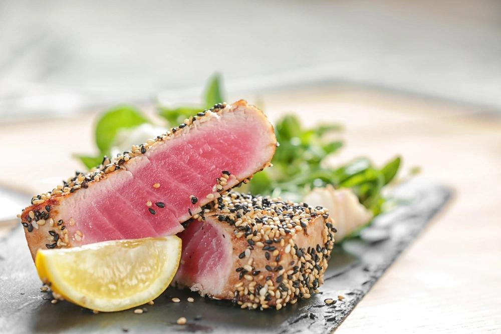 Plate of seared ahi tuna garnished with fresh herbs and served with a side of colorful vegetables