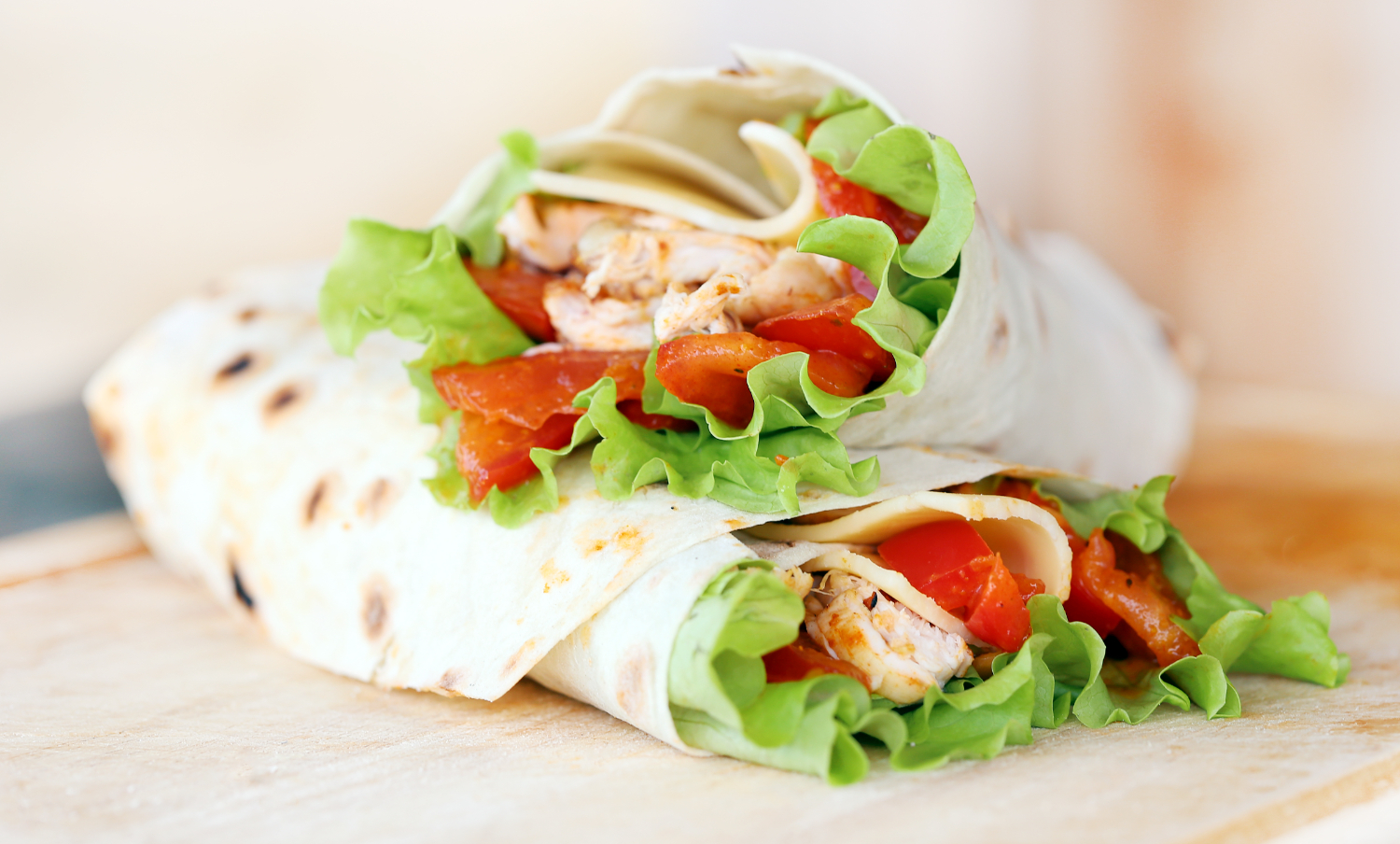 A delicious turkey cranberry wrap filled with sliced turkey, fresh spinach, and a generous spread of cranberry sauce, all wrapped in a whole grain tortilla, served on a wooden cutting board.