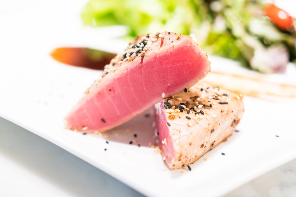 Plate of seared ahi tuna garnished with fresh herbs and served with a side of colorful vegetables