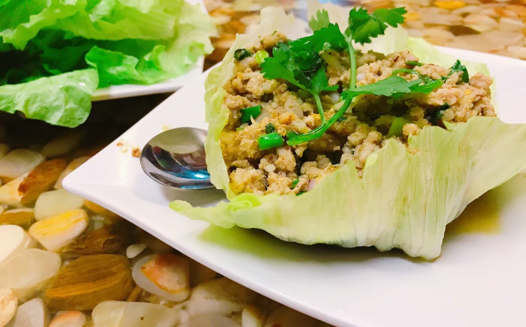 Fresh Thai turkey lettuce wraps featuring crisp lettuce leaves filled with savory ground turkey, colorful vegetables, and drizzled with a tangy peanut or chili sauce, garnished with fresh herbs like cilantro and lime wedges.