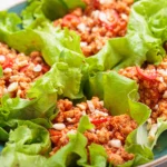 Fresh Thai turkey lettuce wraps featuring crisp lettuce leaves filled with savory ground turkey, colorful vegetables, and drizzled with a tangy peanut or chili sauce, garnished with fresh herbs like cilantro and lime wedges.