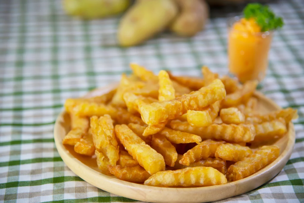 A plate of golden-brown crinkle fries served with a side of ketchup, showcasing their crispy texture and wavy shape.