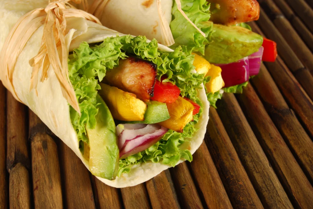 A delicious turkey avocado wrap filled with sliced turkey, fresh avocado, and colorful vegetables, neatly rolled in a whole wheat tortilla.