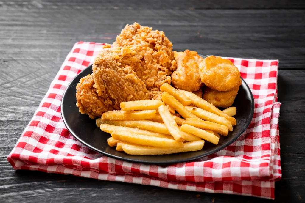 Plate of crispy chicken tenders served with golden French fries and various dipping sauces.