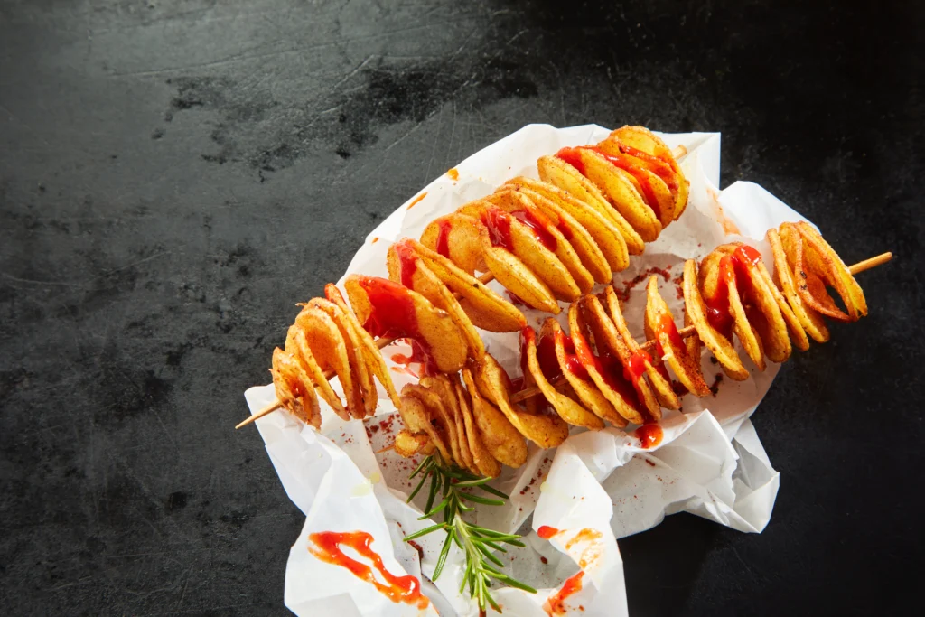 Freshly made golden-brown ribbon fries served in a basket, garnished with seasoning and paired with dipping sauces on the side.