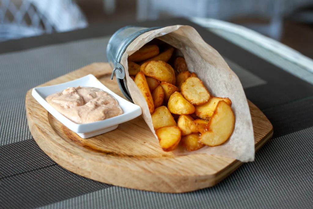 A plate of crispy sidewinder fries, showcasing their unique twisted shape, garnished with various seasonings and served with dipping sauces.