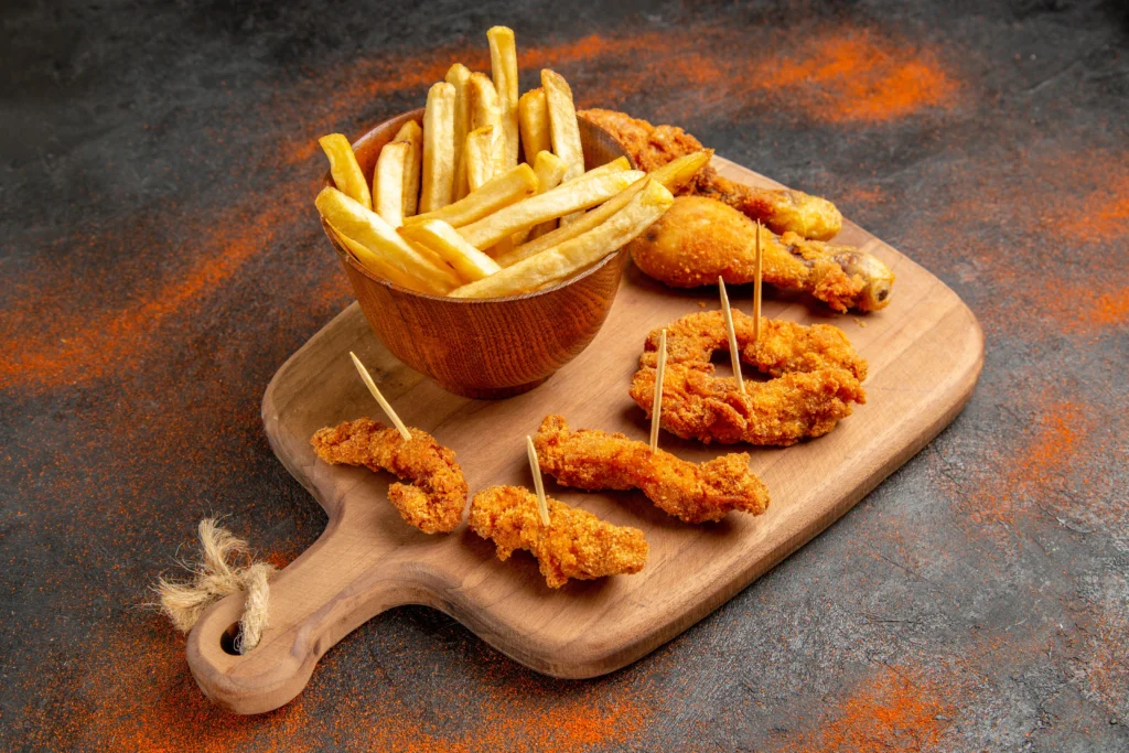 Plate of crispy chicken tenders served with golden French fries and various dipping sauces.