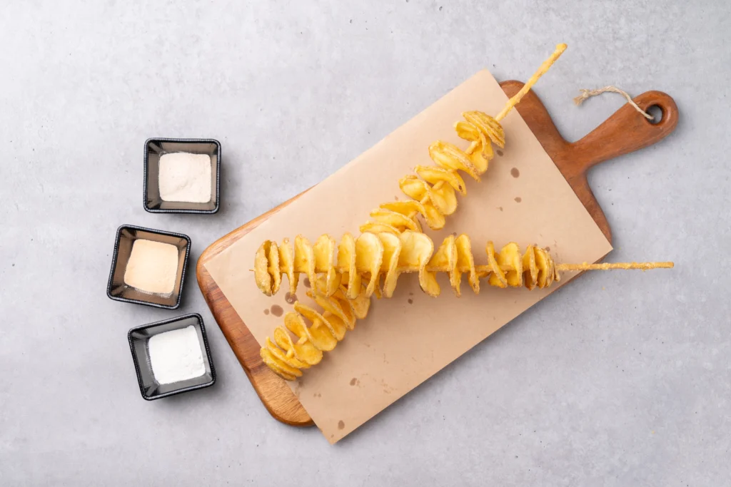 Freshly made golden-brown ribbon fries served in a basket, garnished with seasoning and paired with dipping sauces on the side.