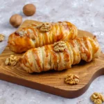 A freshly baked Breakfast Puff Pastry filled with sweet fruits and drizzled with icing, served on a wooden board alongside a cup of coffee and fresh berries, showcasing its flaky texture and inviting appearance.