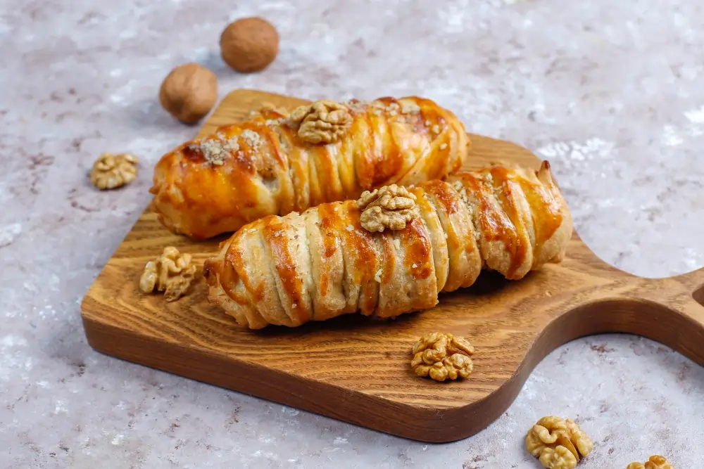 A freshly baked Breakfast Puff Pastry filled with sweet fruits and drizzled with icing, served on a wooden board alongside a cup of coffee and fresh berries, showcasing its flaky texture and inviting appearance.