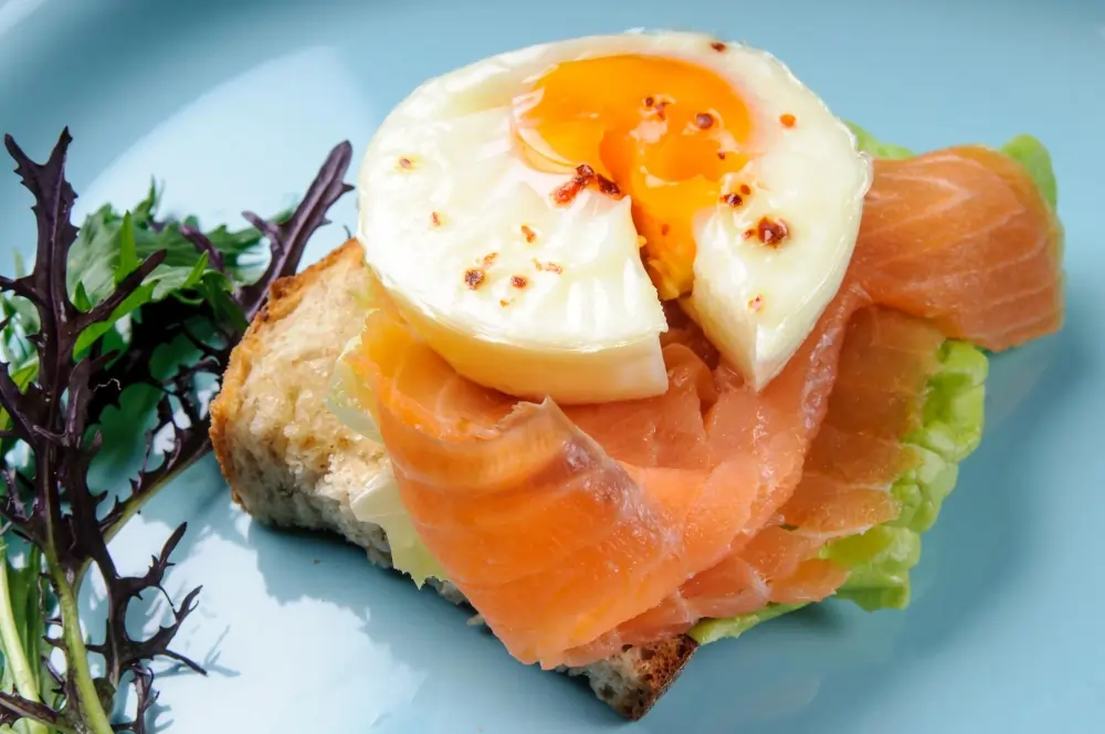 "Close-up of a delicious meal consisting of baked salmon and poached eggs, complemented by sautéed spinach and cherry tomatoes."