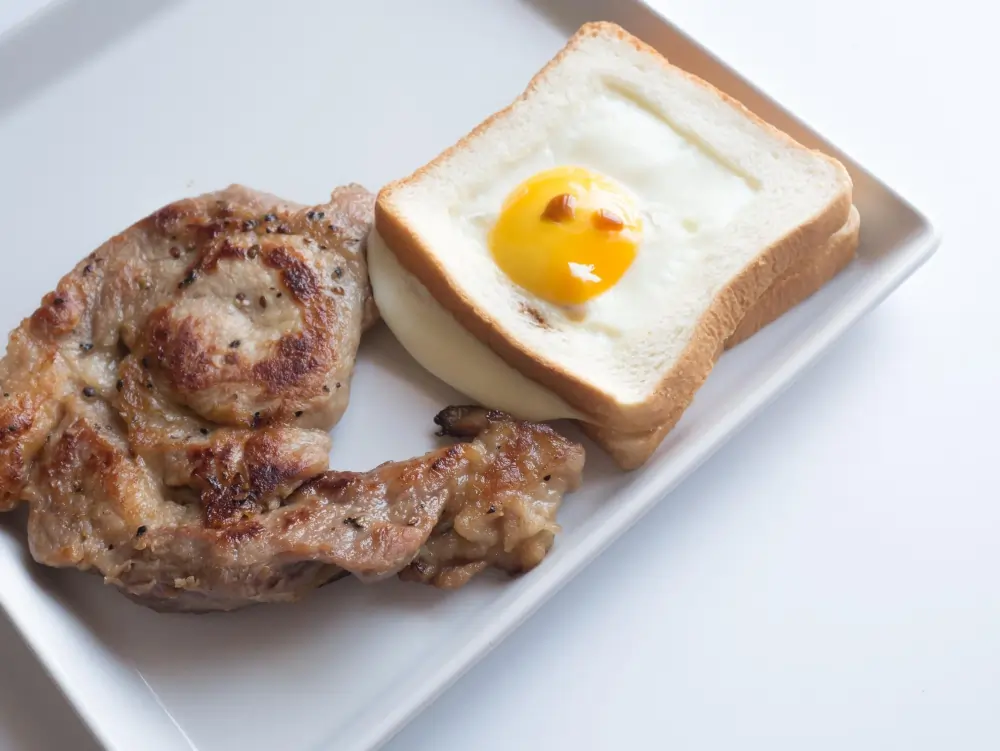 "A hearty breakfast plate featuring scrambled eggs, golden-brown grilled chicken, and a side of fresh vegetables, served on a white plate with a sprinkle of herbs."