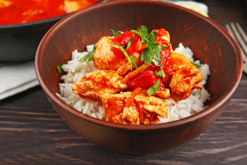 Spicy Chicken Bowl: A colorful bowl filled with tender spicy chicken, fluffy rice, fresh vegetables, and a sprinkle of herbs, showcasing a delicious and healthy meal.