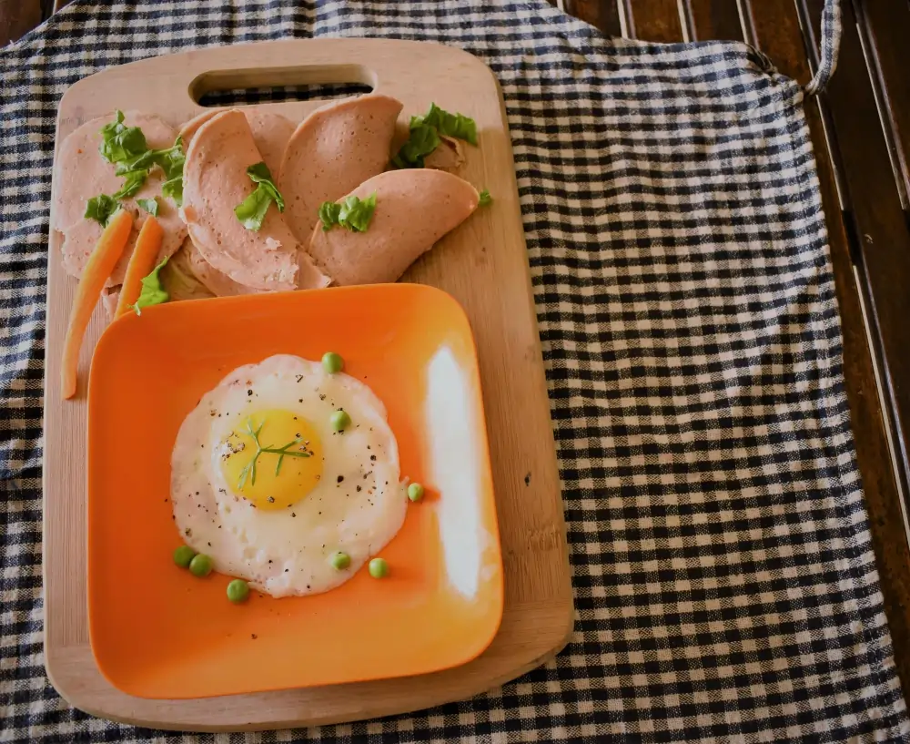 "A hearty breakfast plate featuring scrambled eggs, golden-brown grilled chicken, and a side of fresh vegetables, served on a white plate with a sprinkle of herbs."