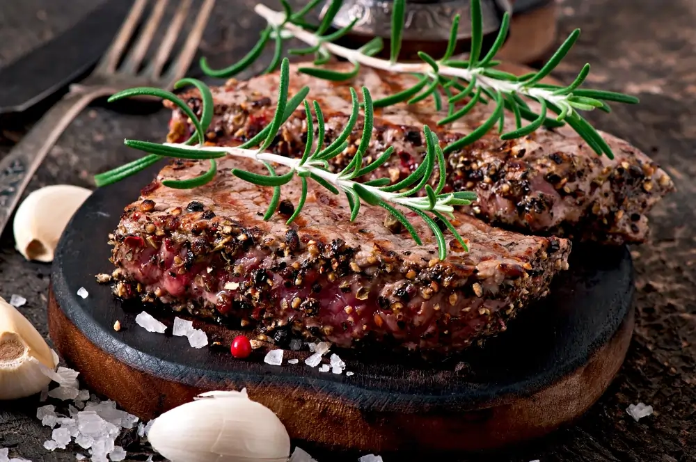 A beautifully cooked black pepper angus steak, perfectly seared and garnished, showcasing its juicy, tender texture with a sprinkle of freshly cracked black pepper on top.