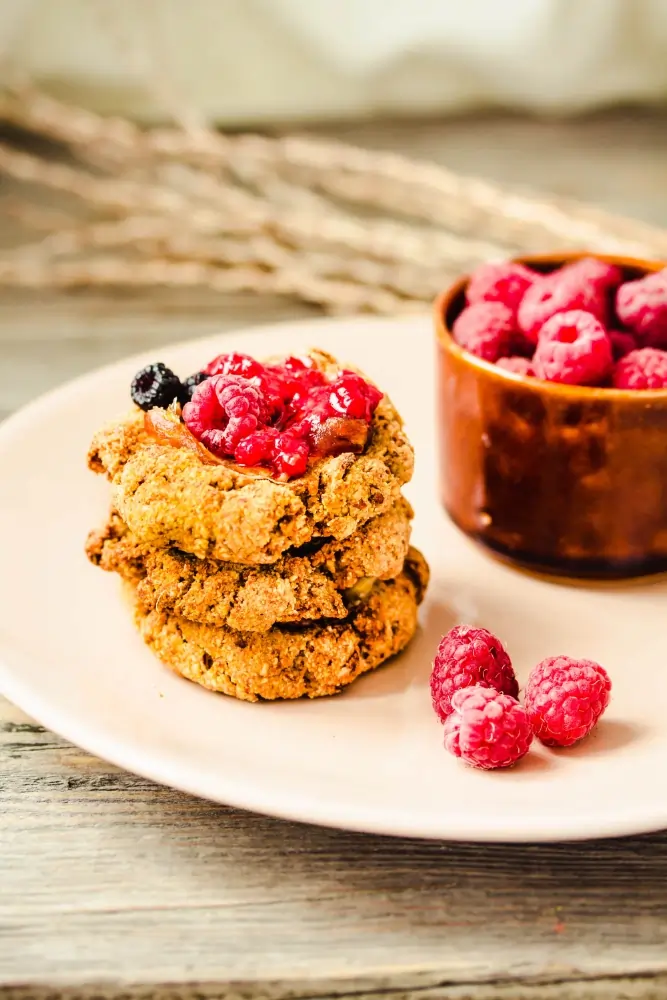 Golden-brown almond flour breakfast cookies with chocolate chips on a rustic plate, surrounded by almonds and cinnamon sticks